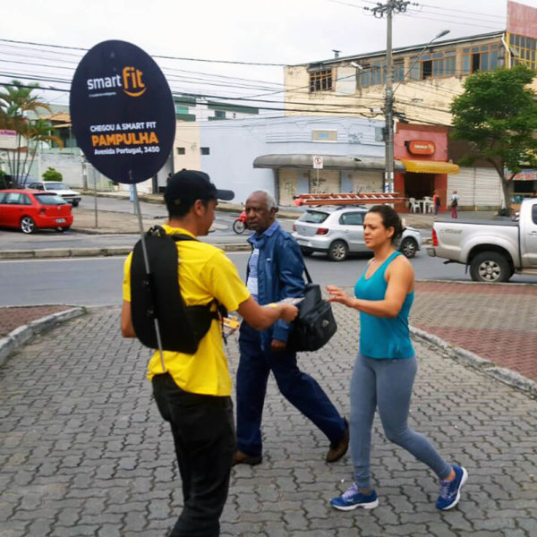 Promotor da Smart Fit entregando panfleto para pedestre