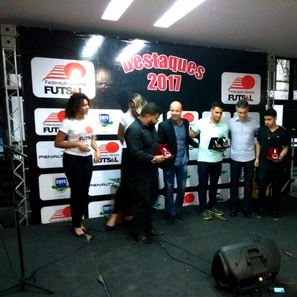 Promotoras da Federação Mineira de Futsal em cima do palco recebendo vencedores
