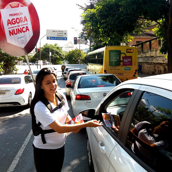 Promotora da Toyota Rodobens entregando flyer no semáforo